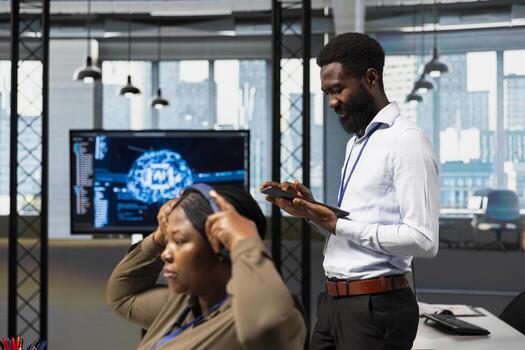 Computer scientist utilizing artificial intelligence to optimize performance using tablet. African american engineer in office training machine learning models with device photo
