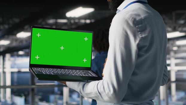 Close up of engineer on data center industrial platform analyzing performance outputs on green screen laptop. Server room IT expert finetuning server rig configurations using mockup notebook photo