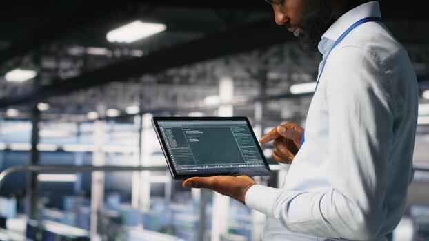 Close up of programmer swiping on tablet display in data center, doing maintenance tasks, ensuring optimal performance. IT expert checks code on device, applying patches to improve stability photo