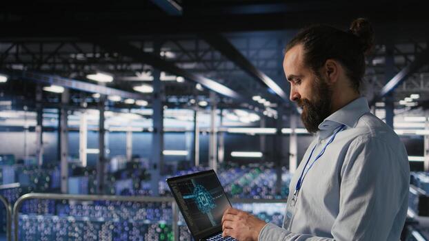 Technician holding laptop walking on server farm platform, doing AI machine learning automatization. Data center programmer using notebook, doing maintenance using artificial intelligence, photo