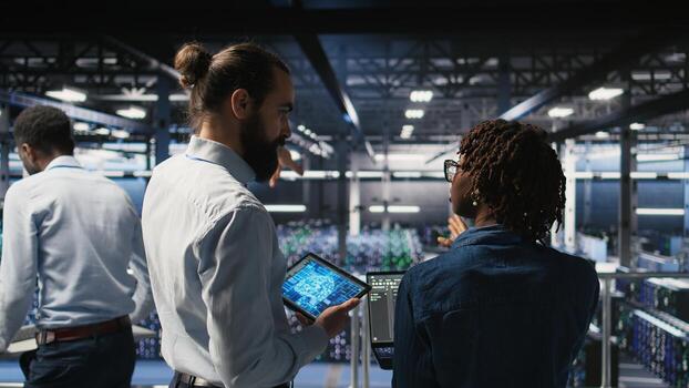 Data center system administrators performing maintenance on supercomputers used for AI. Engineering team managing server hub rigs used for deep learning training, photo