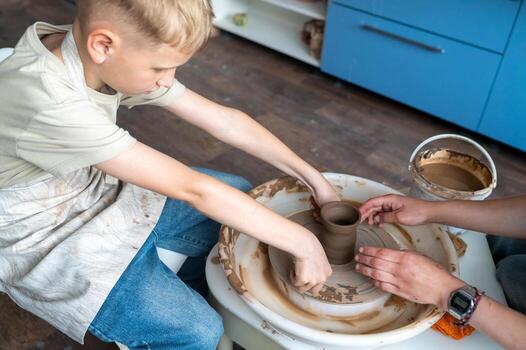 a Child and instructor shaping clay together at pottery workshop photo