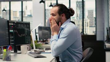 Trader covering face in disbelief, concerned by investment portfolio value drop after unexpected market crash. Upset financial expert distressed by stock exchange account losses, camera B video