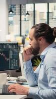 Vertical Trader in office expresses concern as investment portfolio value declines after unexpected market events. Financial professional stressed while reviewing stock exchange account losses, camera A video