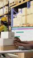 vertikal afrikansk amerikan man använder sig av scanner till bearbeta streckkod och pinne frakt etiketter på lådor från industriell lagring ställ. läser in awb på lim taggar för paket spårning service. kamera a. video