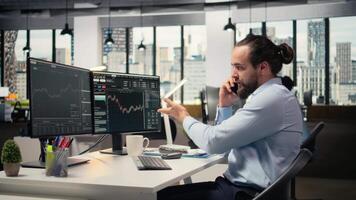 investering konsult talande i telefon ring upp med klient, granskning portfölj prestanda. näringsidkare använder sig av smartphone till do telefon ring upp med kund, tillhandahålla finansiell strategi, kamera en video