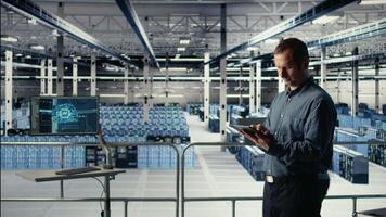 Data center technician monitors machine learning process with tablet, reviewing operational metrics. IT expert using device to review neural networks reports during inspection, camera A video