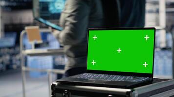 Data center programmers deploying deep learning software on rigs using green screen laptop. Server hub coworkers train AI systems with datasets using mockup notebook to support applications, camera B video