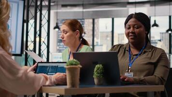 negro mujer de negocios sentado a sala del consejo mesa y resolviendo tareas, inmerso en reporte escritura durante un instrucciones con su equipo. utilizando analítica y indicadores a plan un exitoso proyecto. cámara b. video