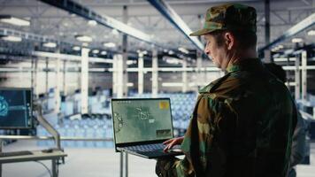 Military technician in data center tracking satellite coordinates using notebook software interface. Army unit in server hub analyzing reconnaissance data through satellite imaging systems, camera A video