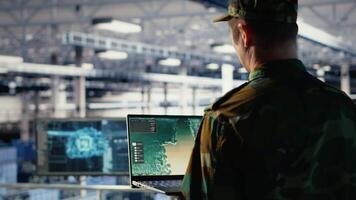 Military engineer in data center tracking satellite coordinates using laptop interface. Soldier in server room analyzing reconnaissance data through satellite imaging systems, camera B video