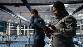 server nav tech Stöd expert- guider företag klienter genom miljö upp säkra företag data säkerhetskopior. afrikansk amerikan kvinna i data Centrum hjälper användare fixera systemet fel på servrar, kamera en video