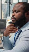 vertical cerca arriba de comerciante analizando valores intercambiar analítica, haciendo pensamiento, evaluando comercio estrategia en apuntalar firma oficina. africano americano hombre lluvia de ideas, evalúa riesgo en financiero mercados, cámara un video