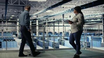 Data center software developers deploy machine learning software on infrastructure racks. Server room IT specialists train AI systems with datasets using tablet to support applications, camera A video