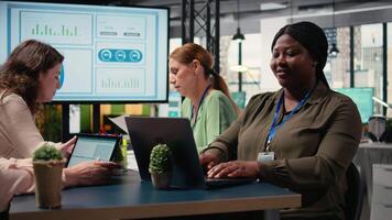 Black businesswoman sitting at boardroom table and solving tasks, immersed in report writing during a briefing with her team. Using analytics and indicators to plan a successful project. Camera A. video