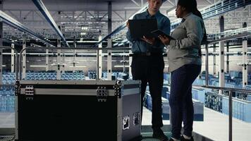 squadra di ingegneri tenere sotto controllo server centro attività utilizzando il computer portatile e tavoletta. lavoro di gruppo dati centro colleghi revisione impianti di perforazione test risultati su dispositivi per garantire sistemi siamo Lavorando correttamente, telecamera un' video