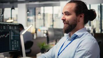 cerca arriba de contento día comerciante análisis valores mercado precio candelero gráficos, haciendo comprar y vender decisiones en oficina. alegre corredor de valores lugares cliente pedidos utilizando comercio plataforma, cámara un video