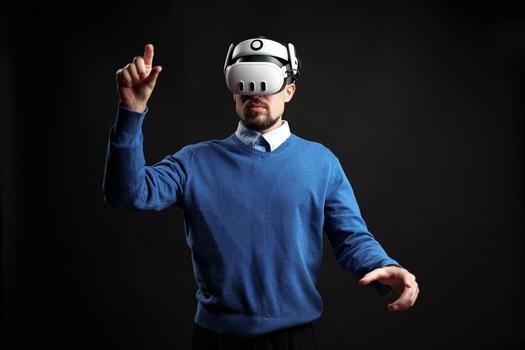 Man engages in virtual reality experience while wearing a headset in a dark studio setting photo