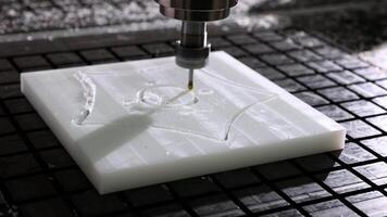 A CNC machine is precisely carving a complex pattern into a white block, showcasing modern manufacturing technology video