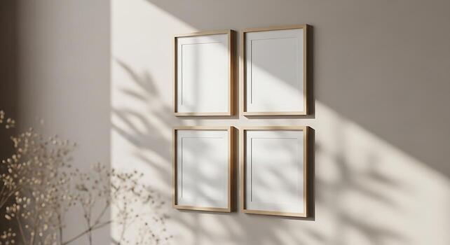 Four empty square picture frames hang on a light green wall with soft natural light and shadow patterns photo