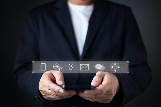 A businessman in a suit holds a smartphone with floating icons for contact options, including phone, email, location, chat, and global web, emphasizing accessibility and connectivity for contact us. photo