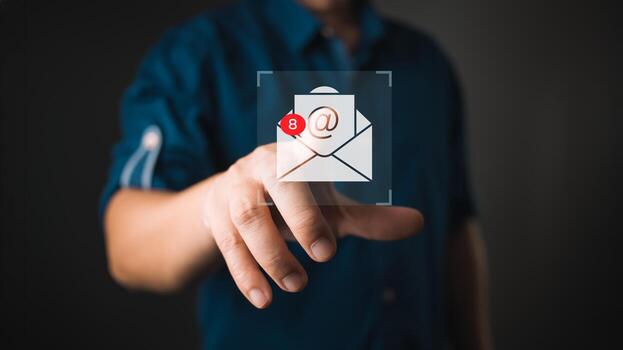 A person in a blurred background interacts with a virtual icon of an email envelope displaying eight notifications, symbolizing unread messages, digital communication, and email alerts. photo