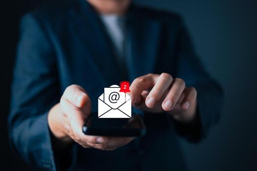 businessman in suit interacts with a digital email notification icon hovering above his smartphone. The glowing envelope with symbol and a red alert signifies mail, inbox updates, and communication. photo