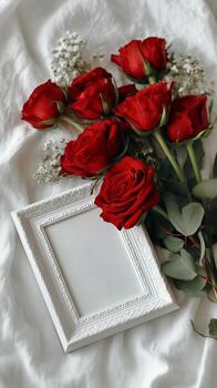 Red Roses and Empty Frame on White Fabric Create a Romantic Setting for Memories and Moments photo