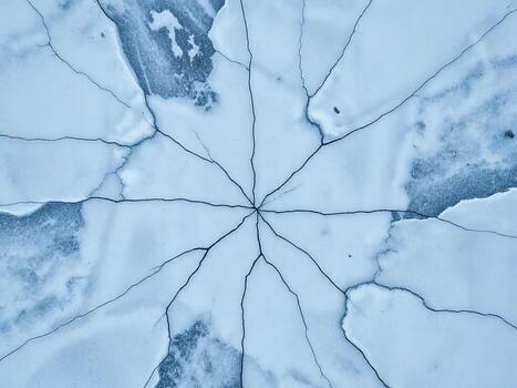 Cracked ice surface in shades of blue with intricate patterns photo