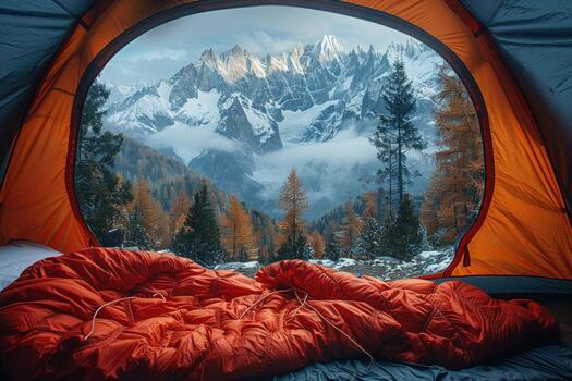 A breathtaking view of snowcapped mountains from inside a tent, with a red sleeping bag in the foreground. photo