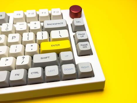 keyboard with bright Enter key on bright yellow background, minimalism, keyboard buttons. A keyboard with a yellow key on the bottom left photo