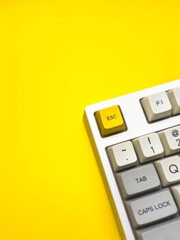 vertical keyboard with bright Esc key on bright yellow background, minimalism, keyboard buttons. A keyboard with a yellow key on the bottom left photo