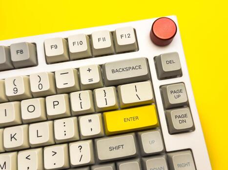 mechanical keyboard with bright Enter key on bright yellow background, minimalism, keyboard buttons. A keyboard with a yellow key on the bottom left photo