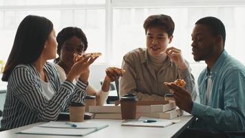 grupo de diverso Universidad estudiantes reunir alrededor un mesa a estudiar. ellos compartir Pizza y café, comprometido en animado discusión, creando un colaborativo y agradable aprendizaje ambiente. video