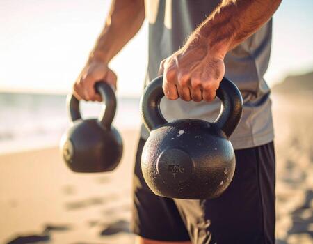 Person holding kettlebells on beach during fitness training, showcasing strength and determination in serene environment. sun sets in background, creating warm atmosphere photo