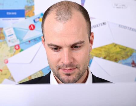 Man examines collection of unread messages and notifications, surrounded by chaotic backdrop of envelopes and maps, reflecting digital landscape of communication photo