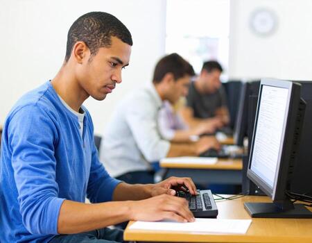 A man is sitting at a desk with a computer photo
