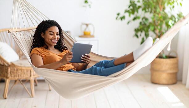 A young woman is relaxing in a hammock and using a tablet computer photo