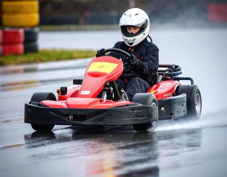 A person riding a go kart on a wet track photo