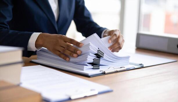 A person in a suit is holding a stack of papers photo
