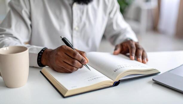 A man writing in a notebook at his desk photo