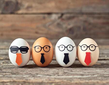 Four eggs with glasses and ties stand on rustic wooden surface, showcasing playful and whimsical design photo