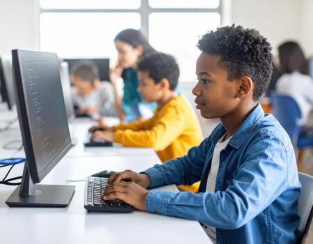 A young boy is using a computer in a classroom photo