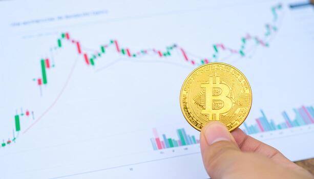 Hand holding golden cryptocurrency coin with financial chart background showing market trends and trading data, symbolizing digital currency investment and analysis photo