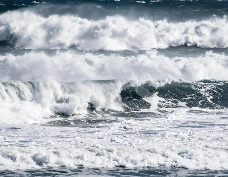 Powerful ocean waves crash against shore, creating stunning display of white foam and rhythmic motion. scene captures beauty and energy of nature force photo