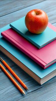 Apple on books with pencils on desk photo