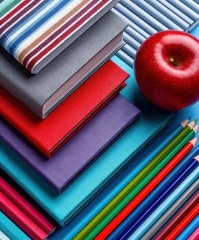 A stack of books, pencils and an apple photo