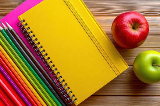 Colorful pencils and an apple on a wooden table with copy space photo