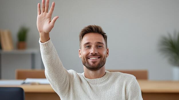 Smiling man waving with raised hand bright office setting, expressing enthusiasm and engagement photo