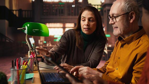 Multiethnic colleagues team writing class notes at the library, studying and reading in the college campus. Working together on learning and preparing for their diploma thesis. photo